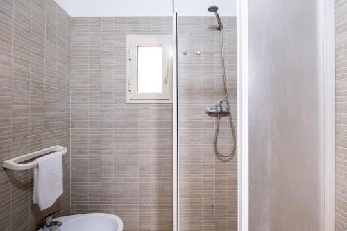 a bathroom with a shower with a toilet and a window at On The Beach San Foca in San Foca