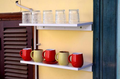 a row of cups and mugs sitting on shelves at LushStay Hanoi Train Street - Cozy in Hanoi
