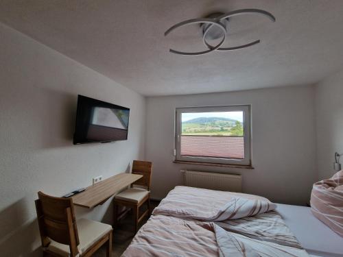 a bedroom with a bed and a desk and a window at Ferienwohnung Strohbergblick in Schichtshöhn