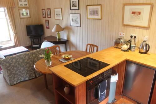 a kitchen and living room with a stove and a table at Glenfield in Lochailort