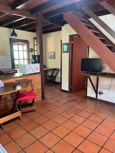 a room with a kitchen with a table and a tv at Chalé Lumiar M&C in Lumiar