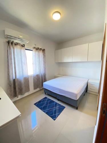 a small bedroom with a bed and a blue rug at Casa confortável perto da praia in Guaratuba