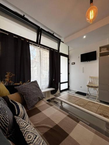 un salon avec un canapé et quelques fenêtres dans l'établissement T2 confortable avec climatisation à 100 m de la plage - 4HOUS34, à Canet