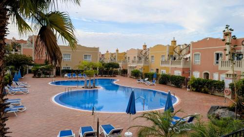 a swimming pool with chairs and umbrellas in a resort at Paraiso en Palmmar in Palm-mar