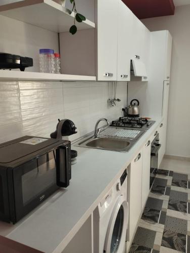 a white kitchen with a sink and a microwave at Casa Orchidea Mazzeo in Mazzeo