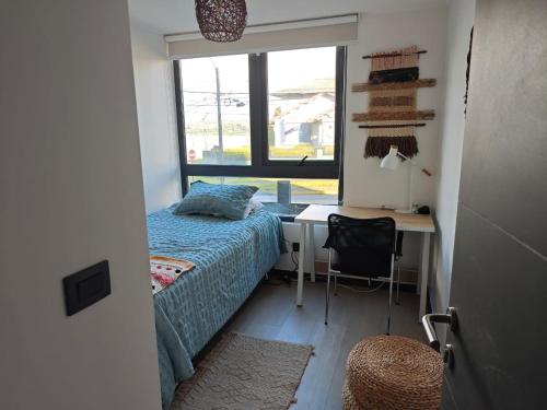 a bedroom with a bed and a desk and a window at Depa con piscina frente al Lago Llanquihue y vista al volcán in Puerto Varas