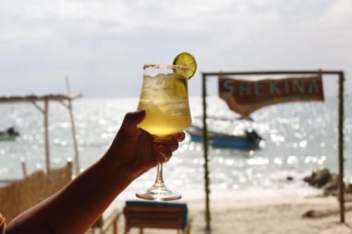 a person holding a margarita with a lime on the beach at Shekina Club House in Playa Blanca