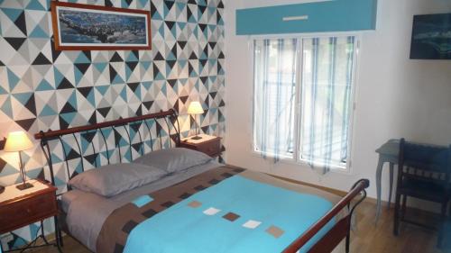 ein Schlafzimmer mit einem Bett und einer geometrischen Wand in der Unterkunft Chambres d'hôtes Le Bas Rassinoux in Saint-Ouen-des-Alleux