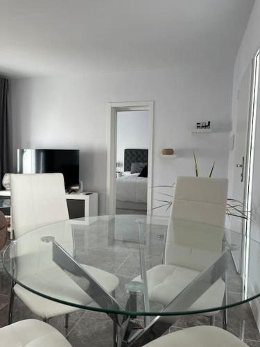a glass table and white chairs in a living room at Casa La Fuente Alta in Algodonales
