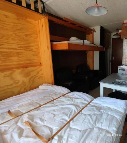 une chambre avec un lit avec une tête de lit en bois dans l'établissement Studio Appartement Grand Serre, à La Morte