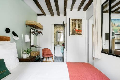 une chambre avec un lit blanc et une chaise rouge dans l'établissement Marais Place des Vosges peaceful air-conditioned, à Paris