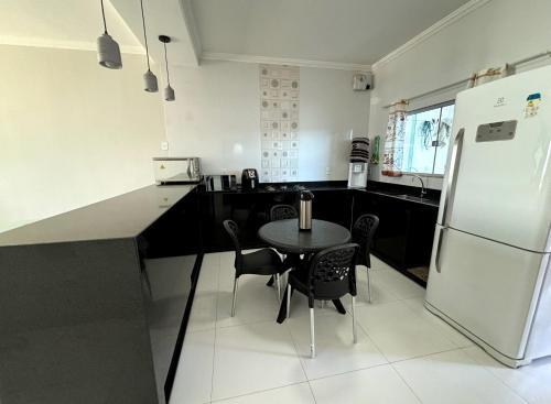 een keuken met een tafel en een koelkast bij Casa de Praia Temporada in Prado