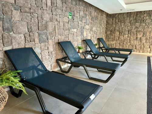 three chairs in a room with a stone wall at Depa con piscina frente al Lago Llanquihue y vista al volcán in Puerto Varas