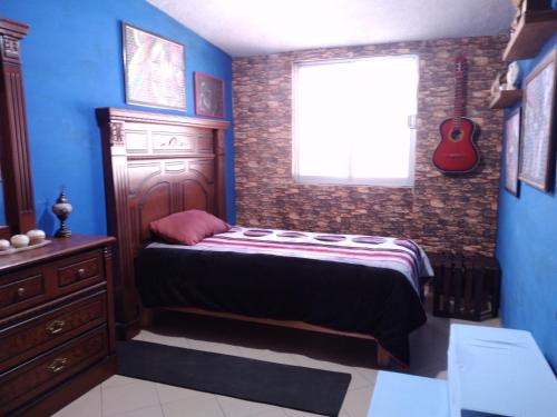 a bedroom with a bed and a window and a guitar at Cómoda habitación para descansar in Toluca