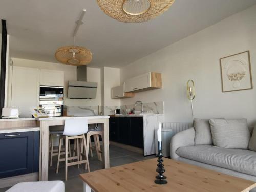 une cuisine et un salon avec un canapé et une table dans l'établissement Appartement de standing Pontaillac, à Royan