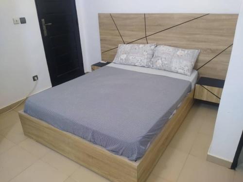 a bed with a wooden frame in a room at Résidence ILEWA proche mer avec Terrasse Fidjrosse Cotonou in Cotonou