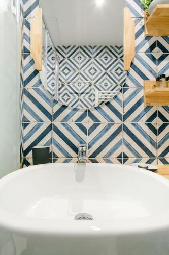 La salle de bains est pourvue d'une baignoire blanche et de carrelage bleu et blanc. dans l'établissement Marais2 Place des Vosges peaceful air-conditioned, à Paris