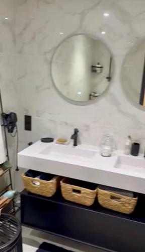 La salle de bains est pourvue d'un lavabo, d'un miroir et de paniers. dans l'établissement Charmant appartement avec vue lac et montagnes, à Sévrier