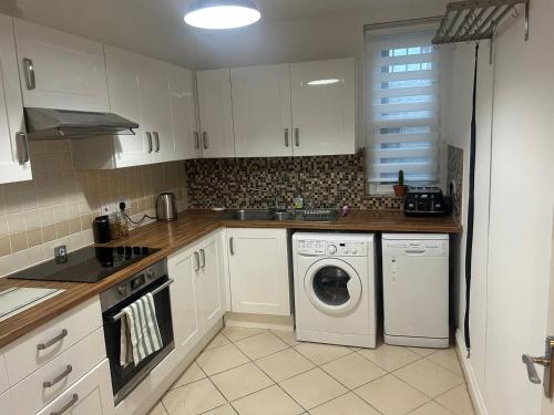 a kitchen with white cabinets and a washing machine at Charming Seafront Retreat in Broadstairs