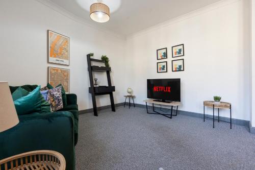 a living room with a green couch and a tv at Mariah Flat - 2 Bedroom getaway in Pontypool in Pontypool