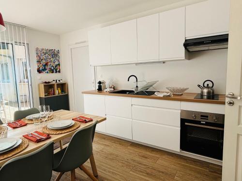 une cuisine avec des armoires blanches et une table avec des chaises dans l'établissement Maison à 10 min d'Angers, à Mûrs-Érigné