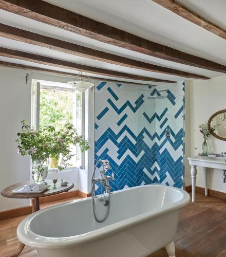 La salle de bains est pourvue d'une baignoire et de carrelage bleu et blanc. dans l'établissement Haute Casussine, à Fauroux