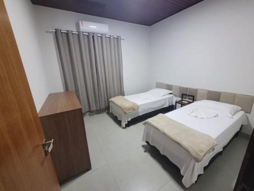 a hotel room with two beds and a wooden door at Casa Ampla Jd Primaveras in Sinop