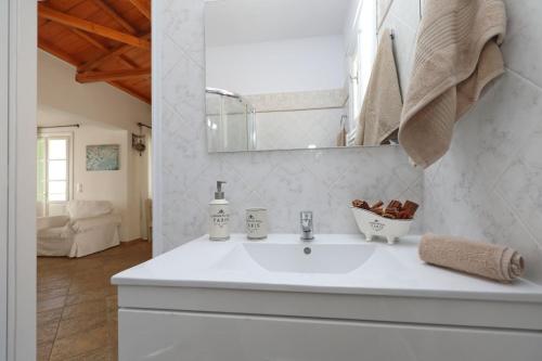 Un baño con un lavabo blanco y un espejo. en Skopelos villa Konstans, en Skopelos Town