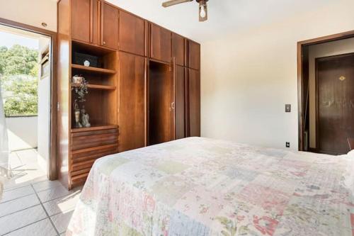 Un dormitorio con una cama grande y un armario de madera. en Suíte da Casa da Mi, en Porto Belo