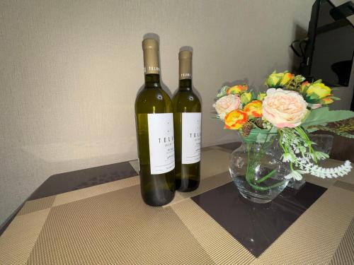 two bottles of wine next to a vase of flowers at Giorgi Apartment In New Gudauri - Block 3 - N315 in Gudauri