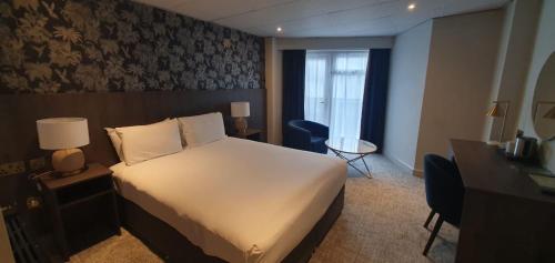 a hotel room with a large bed and a desk at Park hall Hotel & Spa Lancashire, a member of Radisson Individuals in Eccleston