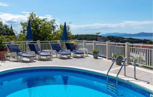a swimming pool with chairs and umbrellas on a balcony at Nice Home In Sumartin With Wifi in Sumartin
