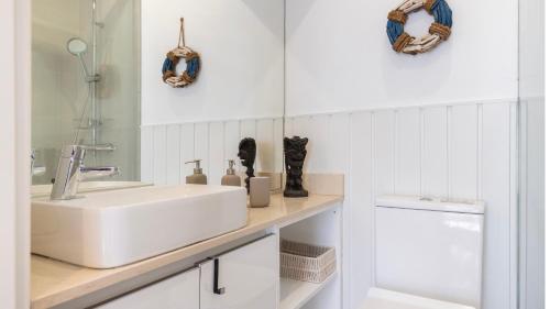 a white bathroom with a sink and a mirror at Pátio Vilareto - Villa Fernanda in São Domingos de Rana