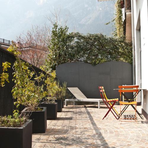 a patio with a bench and a table and chairs at Hotel Garnì Villa Maria in Riva del Garda