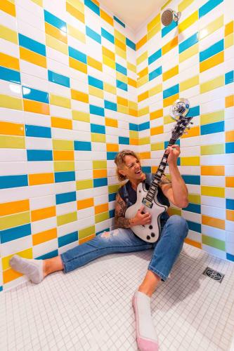 a man sitting on the floor playing a guitar in a room at Hotel Zed Victoria in Victoria