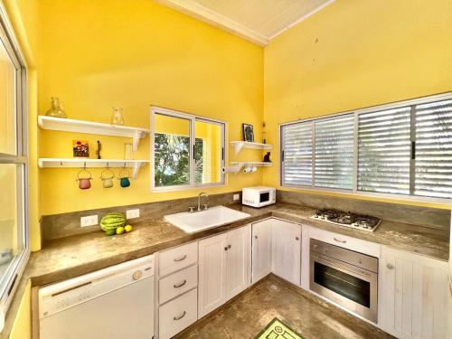 a kitchen with yellow walls and white cabinets and a sink at Casa Amable - Manuel Antonio in Quepos