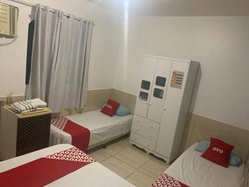 a small room with two beds and a cabinet at Pousada Manhã Serena in Rio das Ostras
