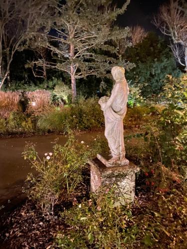 a statue of a man standing on a stone stump at Au Petit Manoir in Socx