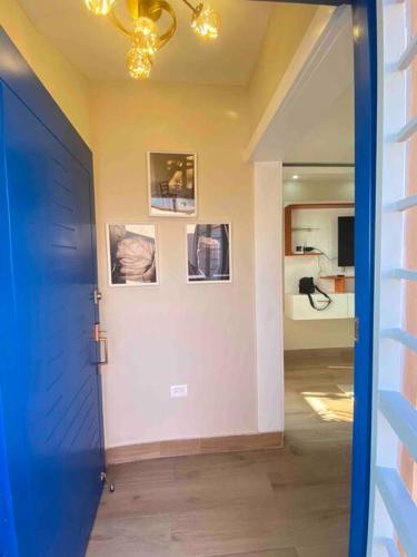 a hallway with a blue door and pictures on a wall at Acogedora partamento cerca de la embajada in Santo Domingo