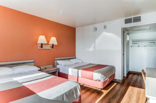 ein Hotelzimmer mit 2 Betten und orangefarbenen Wänden in der Unterkunft Motel 6-Fort Collins, CO in Fort Collins