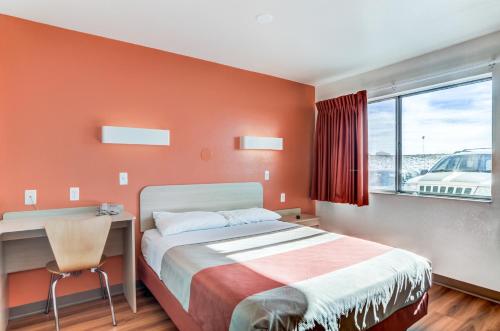 a bedroom with a bed and a desk and a window at Motel 6 Fort Collins, CO in Fort Collins