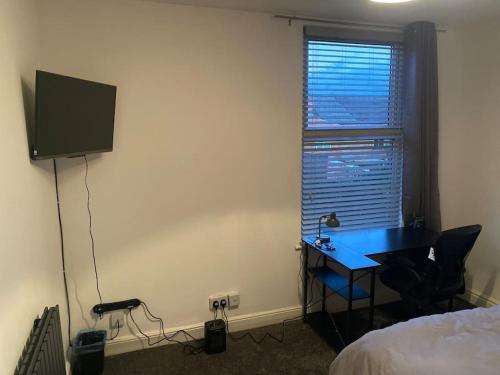 a bedroom with a desk and a television and a bed at Harcourt Road in Nottingham