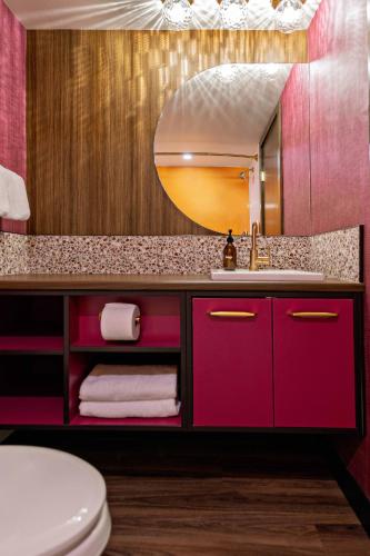 a bathroom with a pink sink and a mirror at Hotel Zed Victoria in Victoria