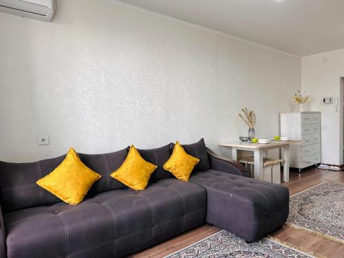 ein schwarzes Sofa mit gelben Kissen im Wohnzimmer in der Unterkunft Солнечная квартира на высоком этаже in Almaty