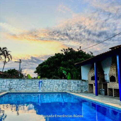a swimming pool in front of a stone wall at Pousada Emerências dos Búzios in Armacao dos Buzios