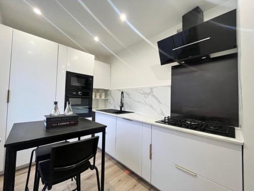 une cuisine avec des placards blancs et une table noire dans l'établissement Magnifique maison en plein centre ville, à Rouen