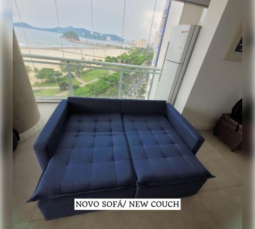 a blue bed in a room with a large window at Book Santos - Unlimited 901 - Frente Mar com Vista Panorâmica in Santos