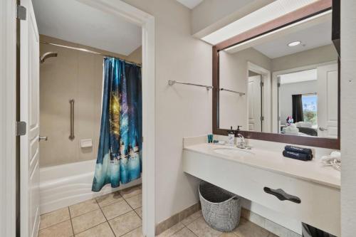 a bathroom with a sink and a tub and a mirror at 5 Minutes to Disney Free Shuttle King & queen bed in Orlando