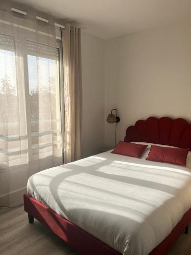 Cette chambre comprend un grand lit avec des oreillers rouges et une fenêtre. dans l'établissement Studio Confort, à Montpellier