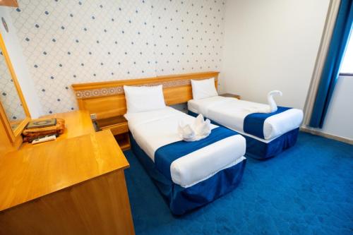 a room with two beds with a cat sitting on them at فندق زاد المجد مكة الروضة in Makkah